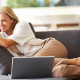 Woman relaxes on grey couch after completing spring HVAC checklist.