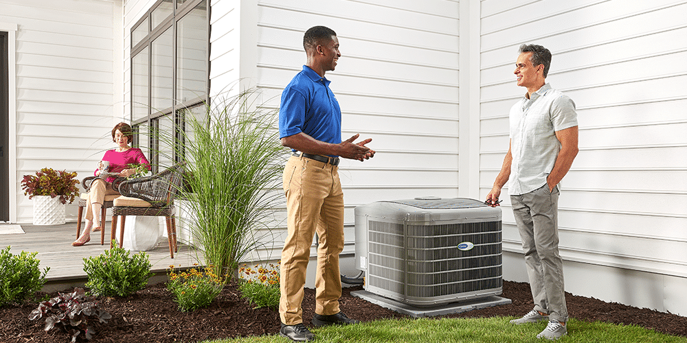 Technician in blue shirt explains to homeowner how air conditioner maintenance is helpful.