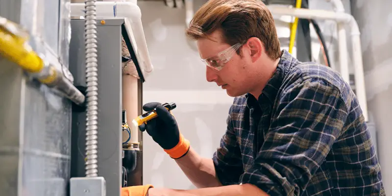 Tech with safety goggles inspects system to determine if a new furnace installation is necessary.