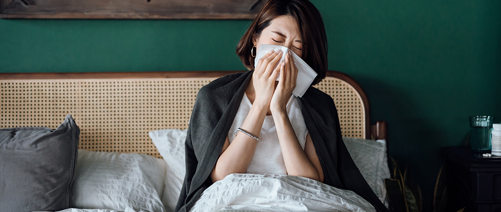 Woman in bed suffers allergies and illness with tissues because of indoor air pollution.