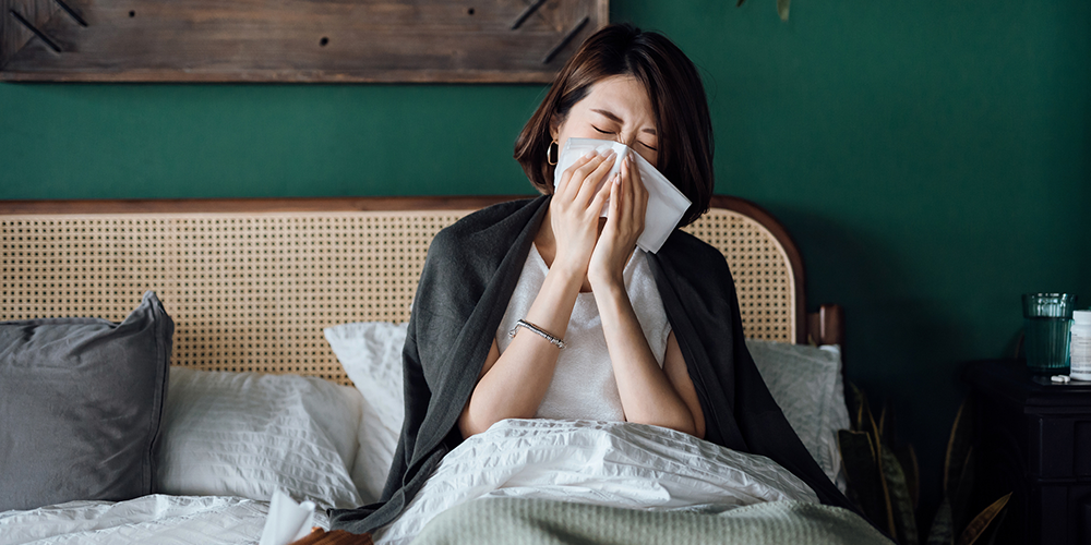 Woman in bed suffers allergies and illness with tissues because of indoor air pollution.